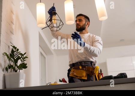 electrician installing led light bulbs in ceiling lamp Stock Photo