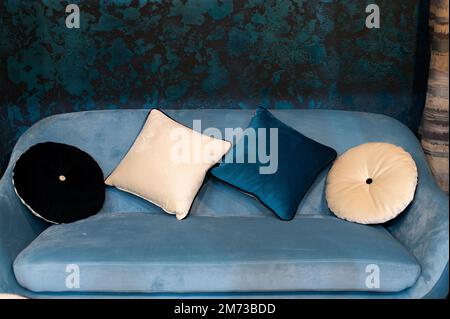 Round and square decorative pillows on a cozy blue sofa, home decor Stock Photo