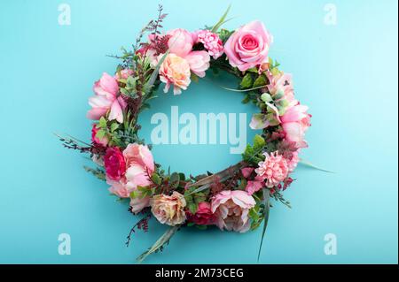 Colorful artificial flowers wreath isolated on light aqua green background Stock Photo