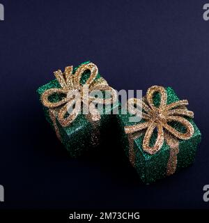Christmas decor green gift boxes with shiny gold bow on dark square background Stock Photo