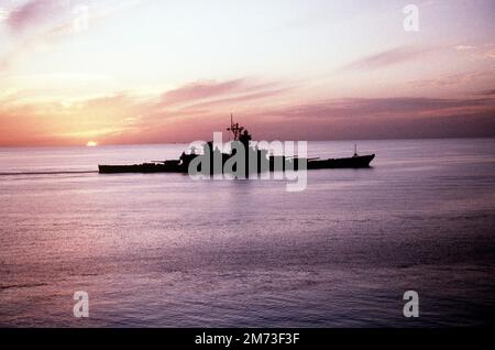 The setting sun silhouettes the battleship USS MISSOURI (BB-63).