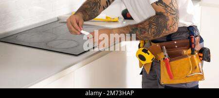craftsman installs hob in kitchen. Household Appliance Installation Services Concept Stock Photo