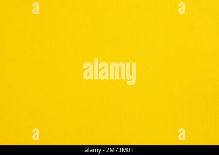 Closeup photo of cardboard sheet surface in solid yellow bright color. Unicolor background. Stock Photo