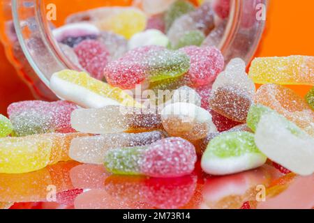 Mixture of sugar coated sweets candy in a glass jar.  On an orange background Stock Photo
