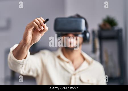 Young hispanic man artist using virtual reality glasses drawing at art studio Stock Photo