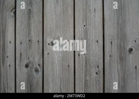 Fence of hardwood planks with texture and pattern of knots, cracks and hammered nails. Natural unpainted wood background. Stock Photo