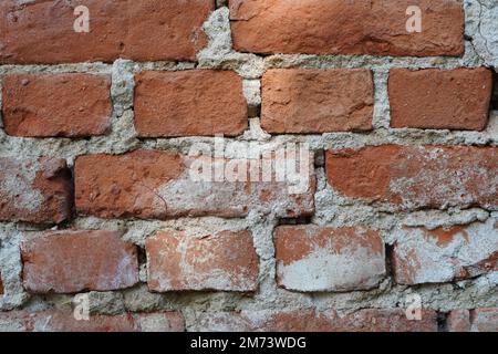Closeup of old red brick wall with layers of unequal bricks glued with cement Stock Photo