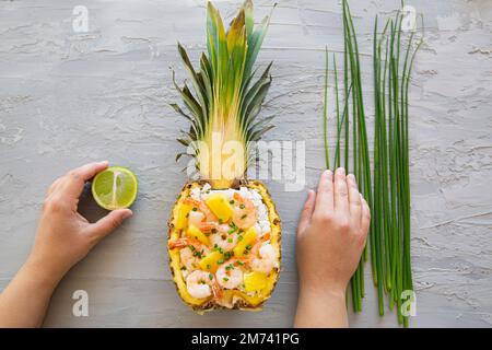 Asian style rice in pineapple with shrimps on grey background, top view. Tasty oriental dish. Stock Photo