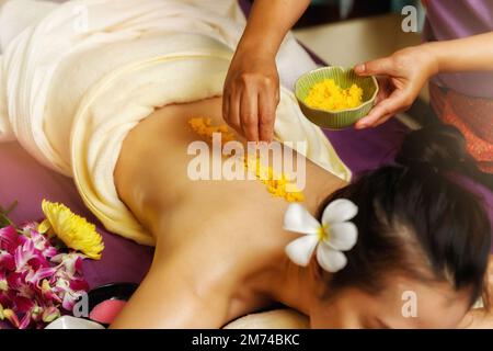 Top view of Spa therapist applying scrub salt on young woman back at salon spa. Hands massaging female back with scrub. Stock Photo