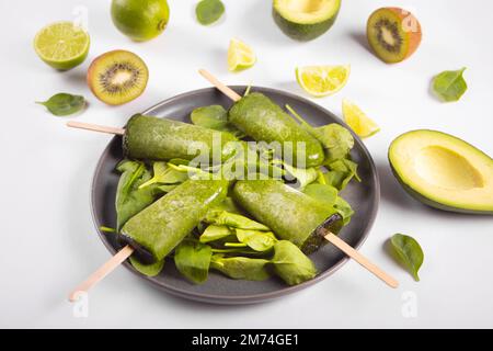 Spinach, kiwi and avocado green raw vegan popsicles ice cream on the plate Stock Photo