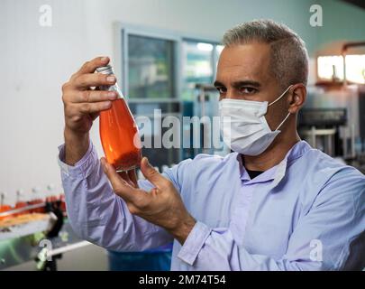 Nutritionists checking the quality of the herbal drinks check the quality of drink basil seed produces on a conveyer belt before distribution to marke Stock Photo
