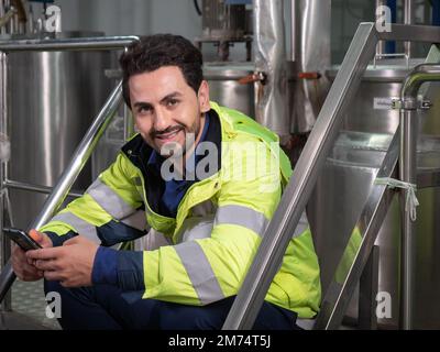 Portrait of smiling factory engineer using a digital tablet in the beverage factory production line. Factory worker controlling production. Stock Photo