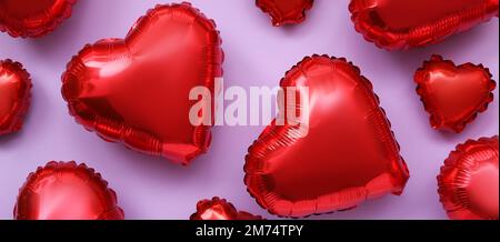 Many heart-shaped balloons on lilac background. Valentine's Day celebration Stock Photo