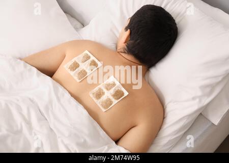 Ill man with mustard plasters on his back lying in bedroom Stock Photo