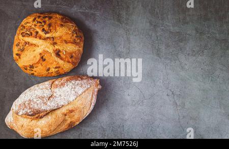 Bakery background with two different freshly baked crispy bread on kitchen table Stock Photo