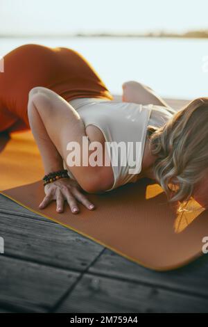 Cropped picture of a yogi woman practicing yoga outside. She is in a cobra yoga pose. Stock Photo
