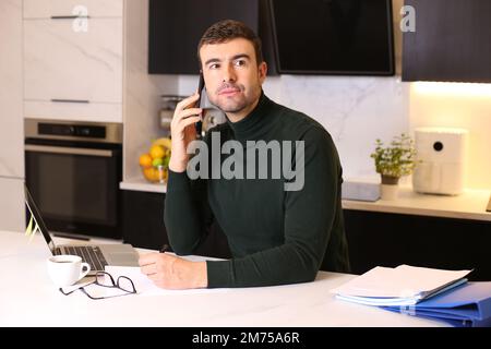 Handsome man calling by phone from home office Stock Photo