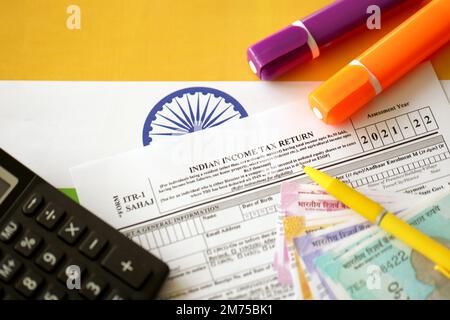 KYIV, UKRAINE - MAY 4, 2022 Indian income tax return blank form with pen and indian rupees bills on indian country flag close up. Annual tax report concept Stock Photo