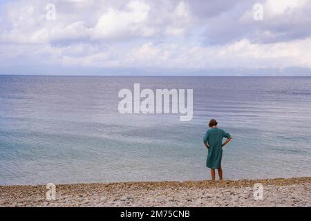 A woman standing on the shore at Modendri Beach on the East coast of Paxos, Greece Stock Photo