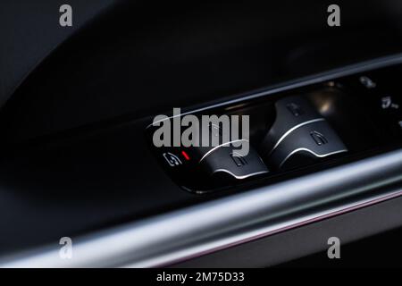 Close up view of button controlling window in modern car interior. Vehicle interior detail. Door handle with windows controls Stock Photo
