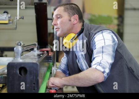 man assembles electronic components on a machine in a factory Stock Photo