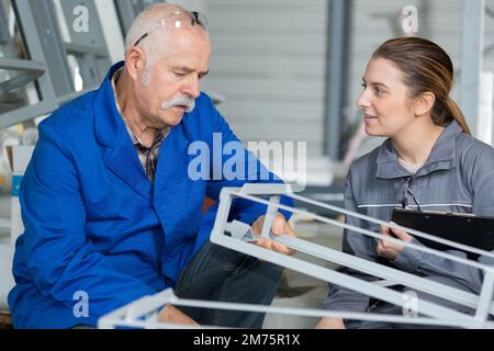 young woman talking to senior worker in factory Stock Photo