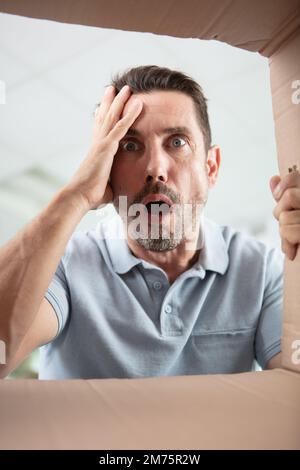 shocked guy looking into empty cardboard box Stock Photo
