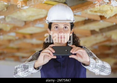 woman uses mobile phone to take photo in construction site Stock Photo