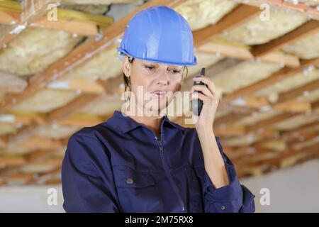young female engineer talking on walkie talkie at factory Stock Photo