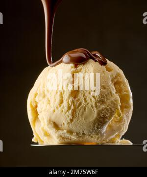 melted chocolate pouring on vanilla ice cream ball on black background Stock Photo
