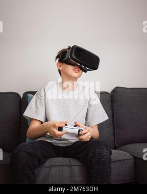 Boy having fun playing simulation games, using virtual reality headset and controller. Children and modern technology concept. Stock Photo
