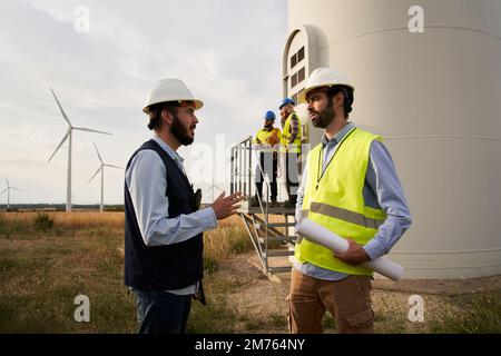 Group of engineers in Wind power station. Renewable and clean energy concept, sustainable future. Stock Photo