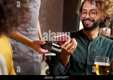 Close up of a Customer making wireless or contactless payment using smartphone in a bar Stock Photo