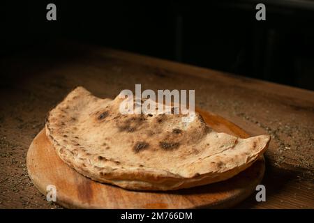 calzone pizza on wooden plate low key Stock Photo