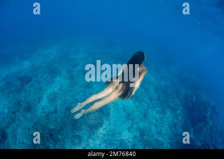 A woman (MR) kicks down below the surface over a reef off the island of Maui, Hawaii. Stock Photo