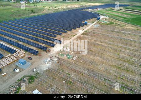 Aerial view of big electric power plant under construction with many rows of solar panels on metal frame for producing clean electrical energy Stock Photo
