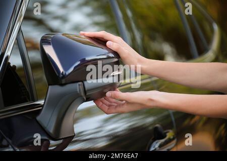 Driver hands adjusting side view mirror of a car Stock Photo
