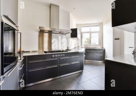 a modern kitchen with black cabinets and stainless steel appliances on the countertops in an apartment interior, london, uk Stock Photo