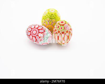 Three pastel quill art Easter eggs with two standing and one on its side against a white background. The image has copy space. Stock Photo