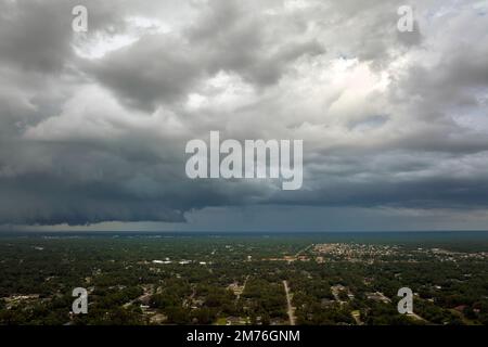 Dark stormy clouds forming on gloomy sky before heavy rainfall over suburban town area Stock Photo