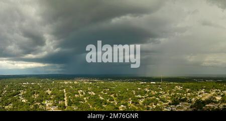Dark stormy clouds forming on gloomy sky before heavy rainfall over suburban town area Stock Photo