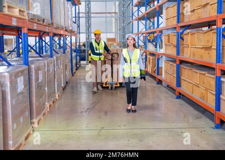 Warehouse worker pull manual pallet hand truck stack with boxes walk ...