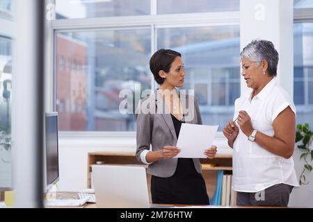 Getting down to the nitty-gritty. two businesswomen discussing paperwork in the office. Stock Photo