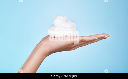 Skincare, wellness and hands with foam on blue background for treatment, grooming and body care. Cosmetics, spa aesthetic and palm with shaving cream Stock Photo