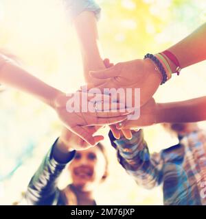 Summer is fun with friends around. A group of friends standing in a huddle with their hands piled. Stock Photo