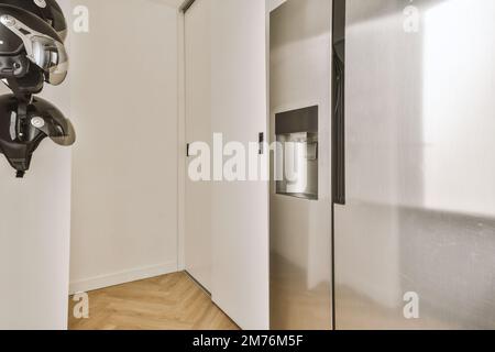 a room with an open door and a bike hanging on the wall next to the refrigerator freezer in it Stock Photo