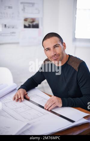 His ideas flow better in an uncluttered environment. Portrait of an architect drafting up building plans. Stock Photo