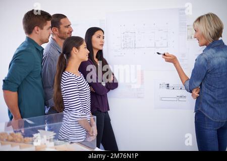 Paying close attention to their instruction. a group of architects discussing plans. Stock Photo