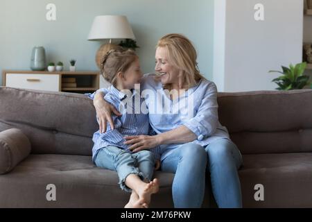 Happy pretty middle aged granny talking to cute granddaughter kid Stock Photo