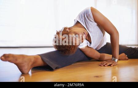 Stretching keeps me at the top of my game. a young woman dancer stretching on the floor. Stock Photo